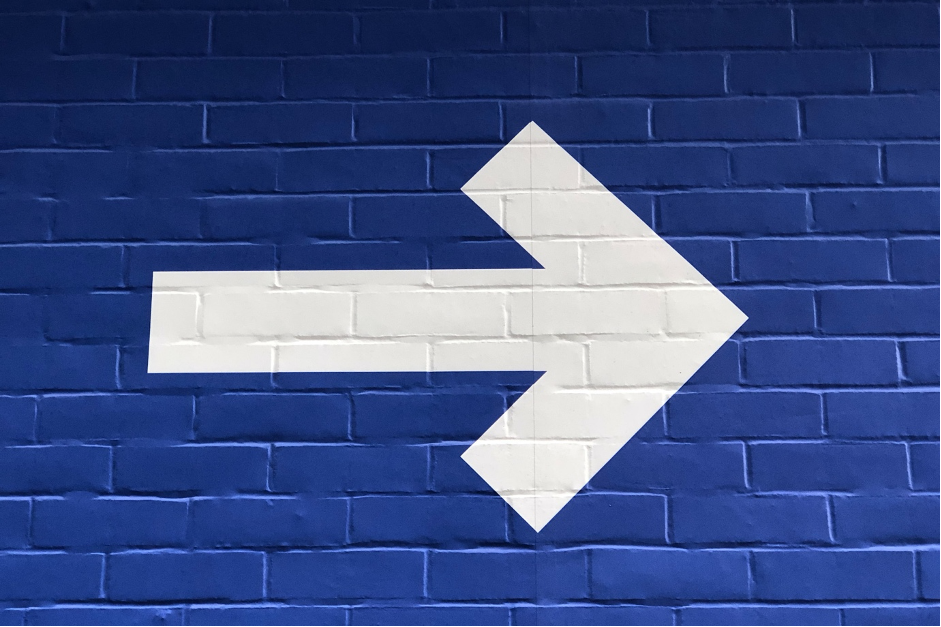 A wall painted blue with a white arrow pointing to the right.