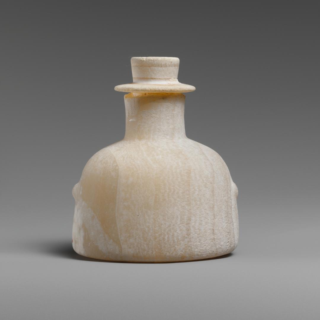 A short stone bottle with a lid that is hat-shaped