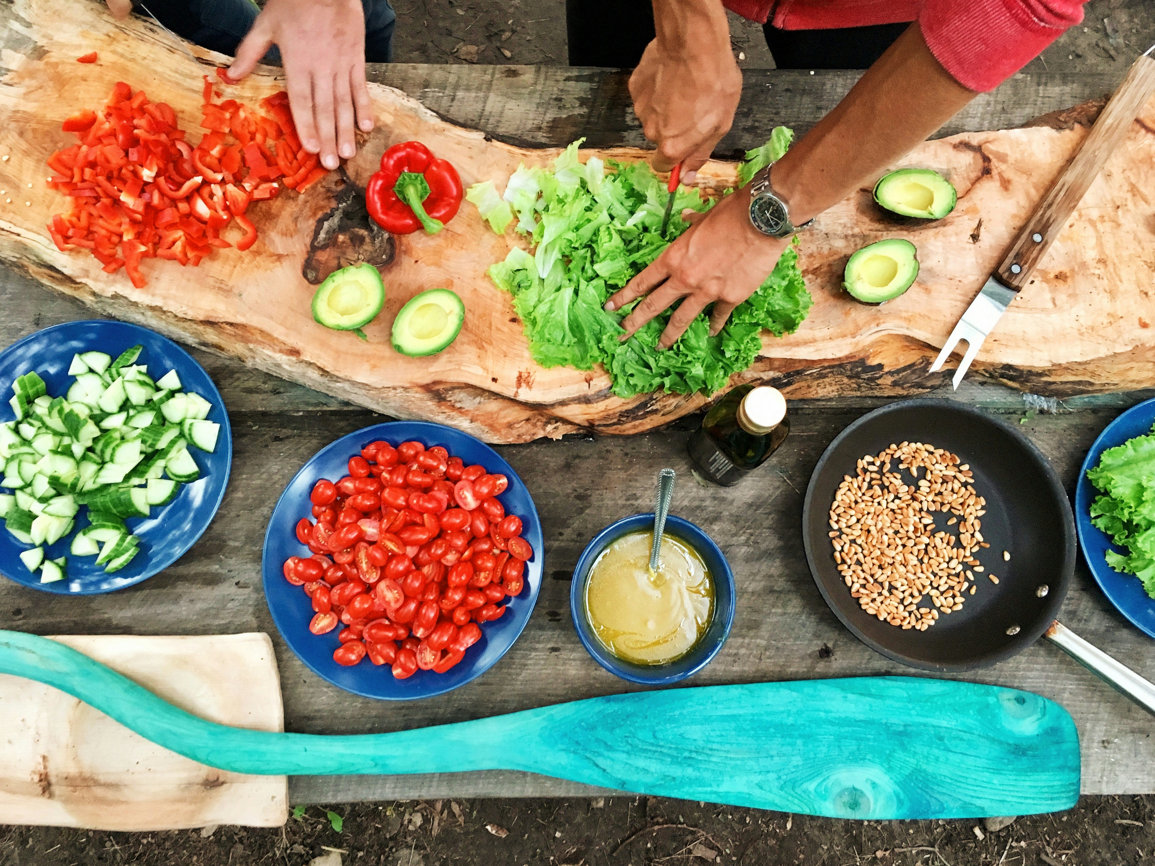 An overhead view of two people preparing salad