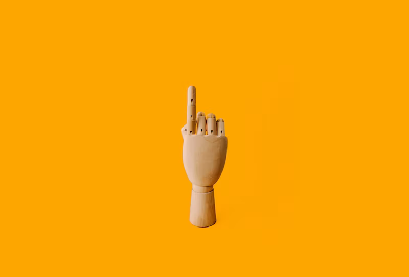 A wooden hand with one finger pointing upwards