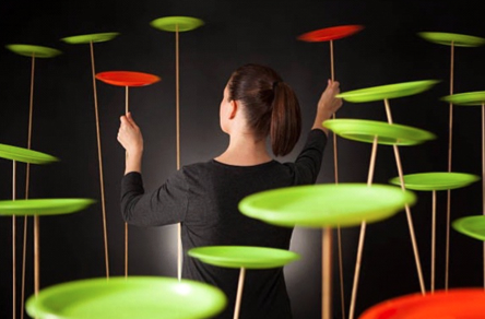 A lady spinning plates on long sticks